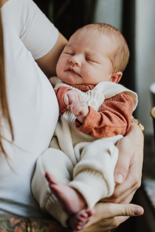 Schlafendes neugeborenes Baby auf Mamas Arm.