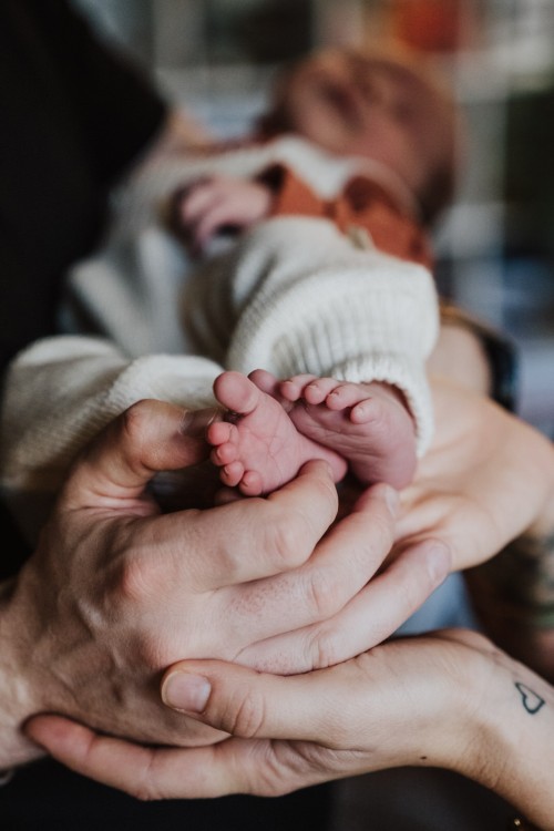 Kleine Babyfüße festgehalten von großen Elternhänden.