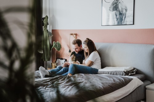 Die jungen Eltern sitzen im Bett und genießen die Zeit mit ihrem Baby