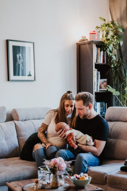 Eltern sitzen mit ihrem Baby im Wohnzimmer.