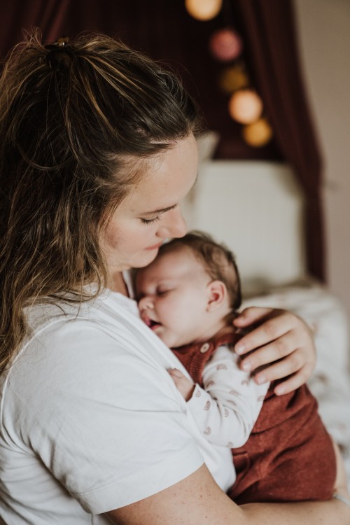 Eine Frau, die ihr schlafendes Baby im Arm hält.