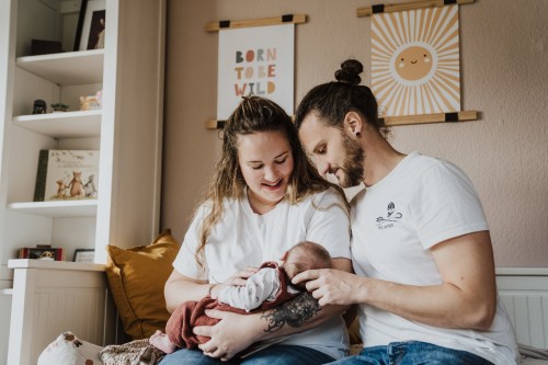 Die jungen Eltern halten ihr neugeborenes Baby.