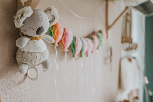 Ein Koalabär, der neben einer Reihe von Papier-Luftballons an der Wand hängt.