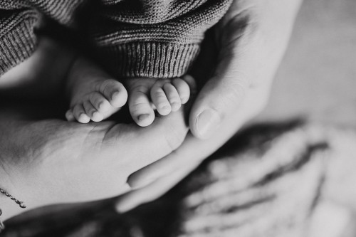 Ein Schwarz-Weiß-Foto von Händen die die kleinen Baby Füße halten.