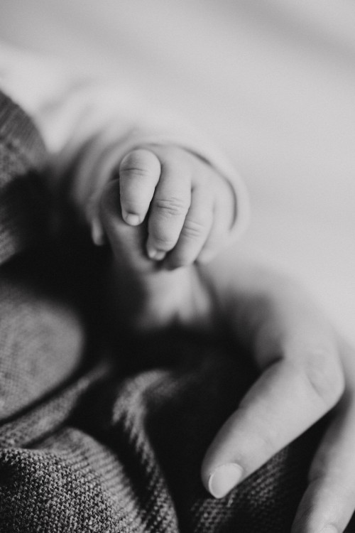 Ein Schwarz-Weiß-Foto von der Hand eines Babys die den Finger der Mutter fest hält.