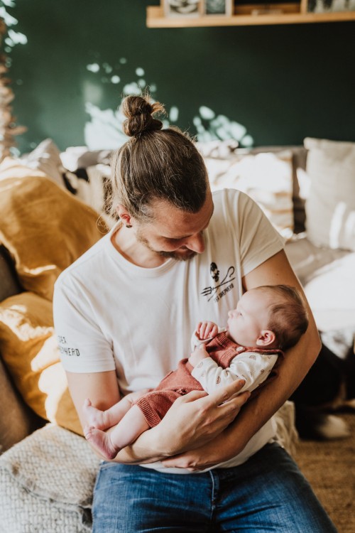 Der Vater hält sein neugeborenes Kind in den Armen.