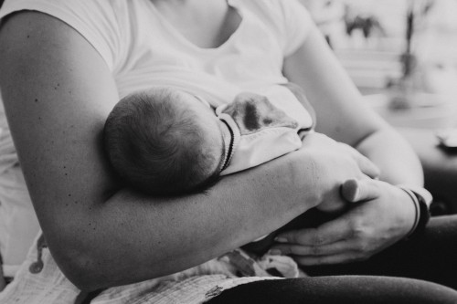 Die Mutter hält ihr neugeborenes Baby auf dem Arm