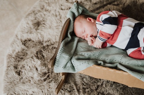 Ein kleines Baby schläft auf einer grüner Decke