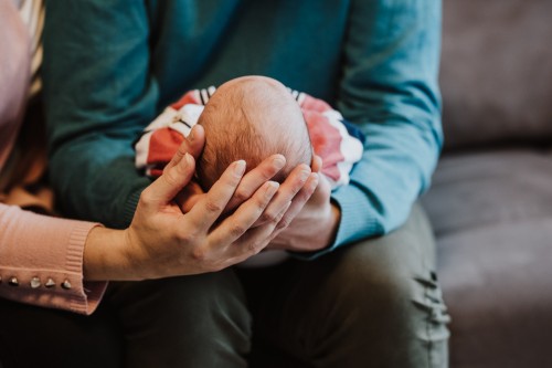 Die Eltern halten ein Baby in den Händen.