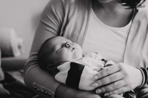 Eine Frau hält ein schlafende Baby im Arm.