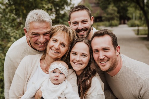 Ein großes Familienbild, alle schauen in die Kamera zu der Familienfotografin Eva Mertzen.