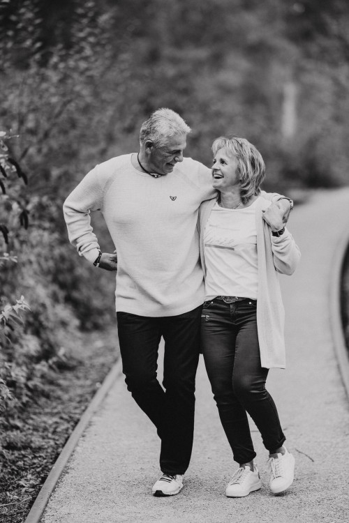Eine Frau und ein Mann gehen umarmt den Weg entlang.
