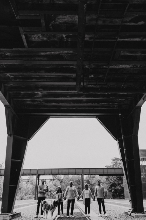 Die ganze Familie mit den Großeltern steht in einer Linie und hält sich an den Händen.