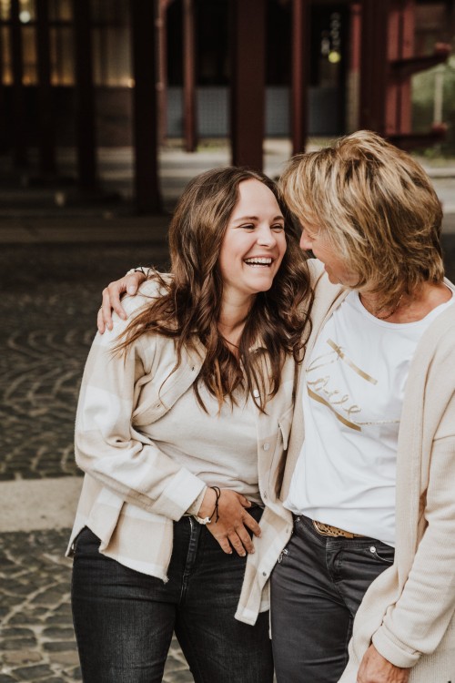 Zwei Frauen umarmen sich und lachen sehr herzlich.
