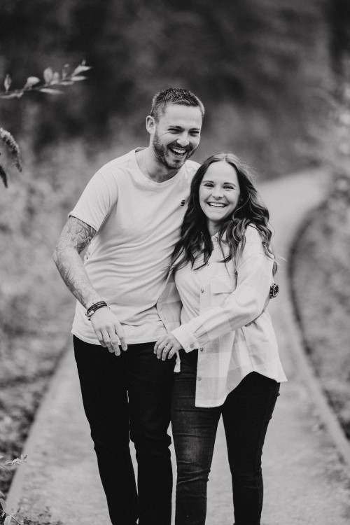 Eine Frau und ein Mann umarmen sich und gehen zusammen den Weg entlang.