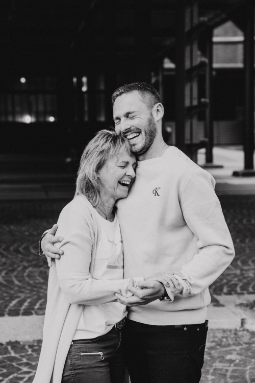 Eine Frau und ein Mann umarmen sich und lachen sehr herzlich.