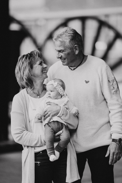 Eine ältere Frau und ein ältere Mann schauen sich an, sie hält ein kleines Baby.