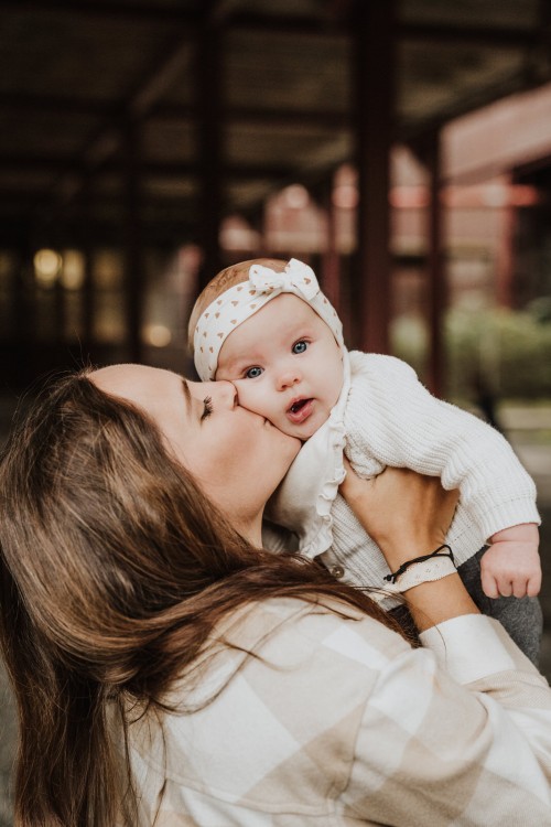 Eine Frau die ein Baby auf die Wange küsst.