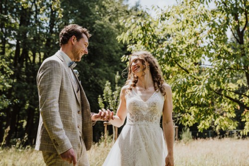 Ein Brautpaar steht auf einer Wiese und schaut sich an.