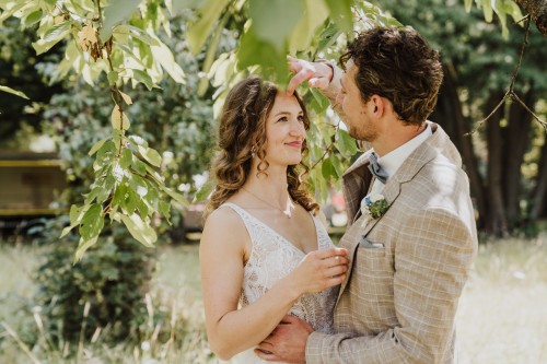 Ein Bräutigam richtet einer Braut die Haarsträhne.