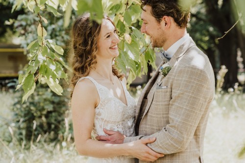 Ein Brautpaar steht unter einem Baum und schaut sich an.