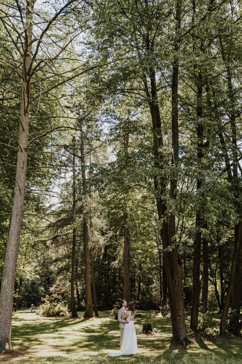 Ein Brautpaar steht mitten im Wald.