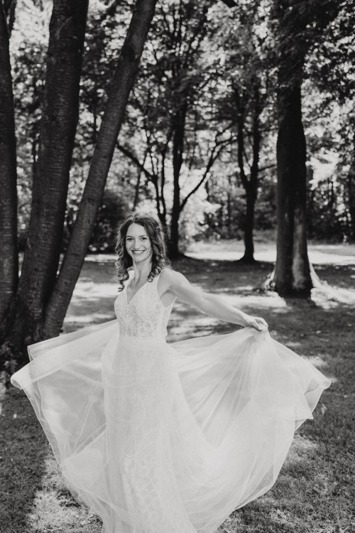 Ein schwarz-weißes Bild von einer Braut die im Wald tanzt.