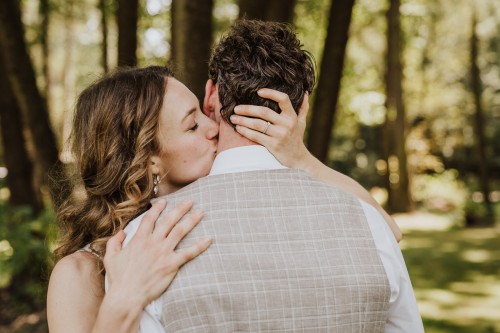 Eine Braut küsst einen Bräutigam am Hals.