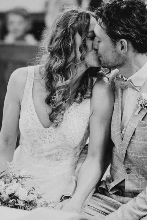 Ein schwarz-weißes Bild von einem Brautpaar, dass sich küsst.
