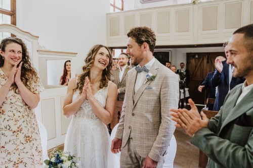 Das Brautpaar und deren Gäste klatschen in die Hände.