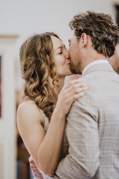 Ein Brautpaar küsst sich in einer Kapelle.