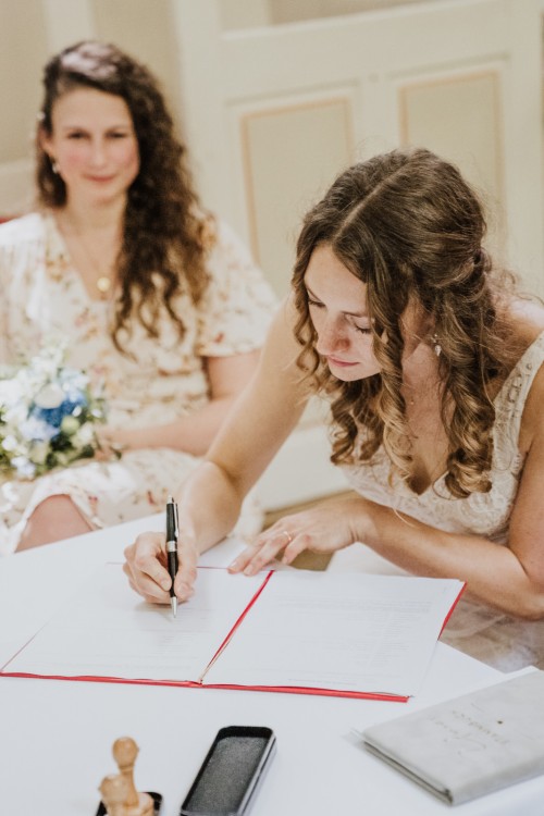 Eine Braut unterschreibt ein Dokument.