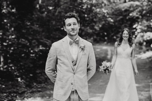 Ein schwarz-weißes Bild von einem Bräutigam und einer Braut im Hintergrund.