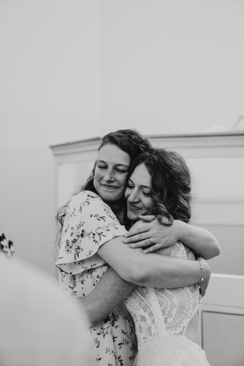 Eine Frau umarmt eine Braut.