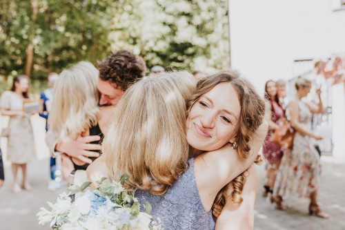 Eine Frau umarmt eine Braut.