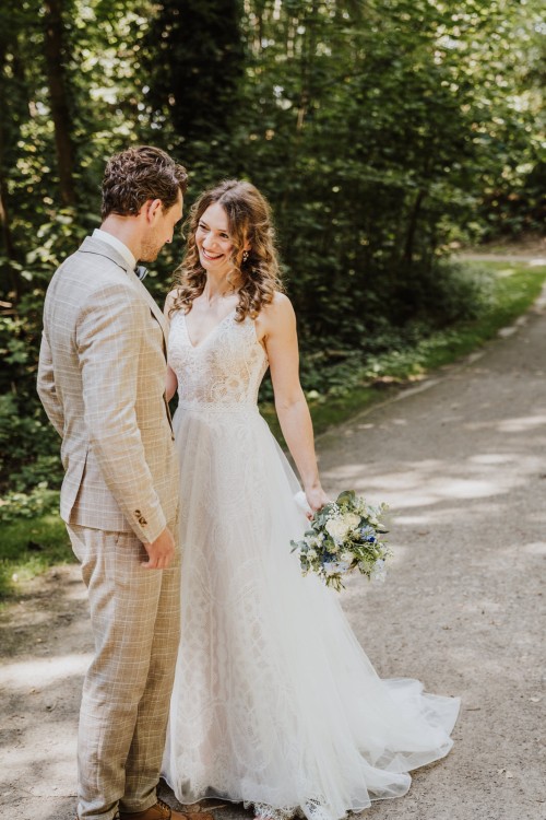 Ein Brautpaar steht im Wald.