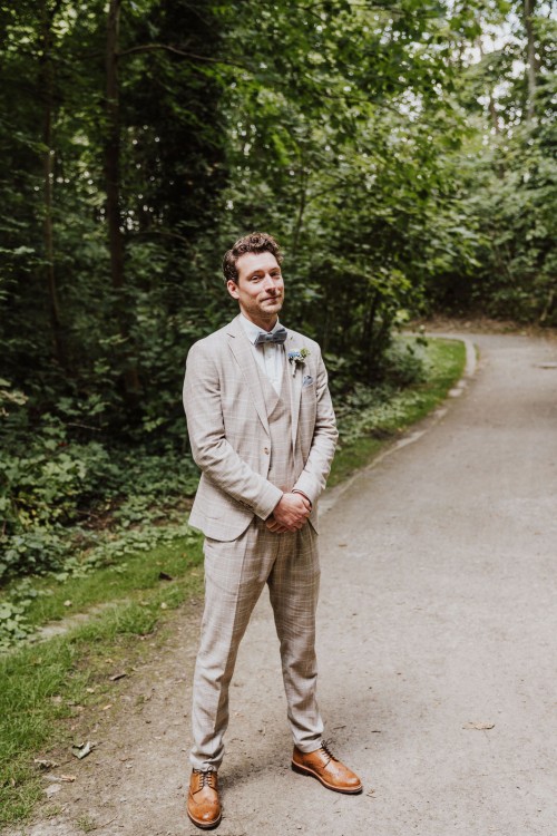 Ein Bräutigam steht im Wald.