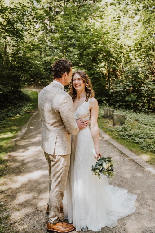 Ein Brautpaar umarmt sich im Wald.