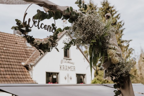 Blumenschmuck und ein Schild auf einem Gestell.