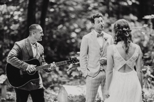 Ein Mann spielt Gitarre und ein Bräutigam singt seiner Braut.