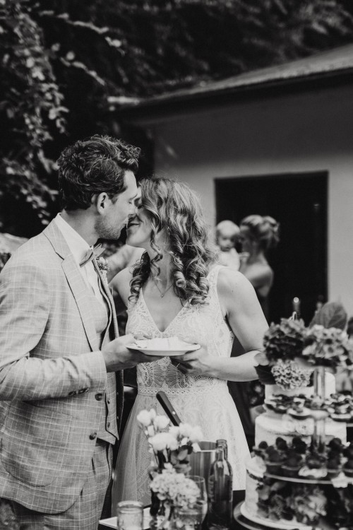 Ein Brautpaar küsst sich vor einer Hochzeitstorte.
