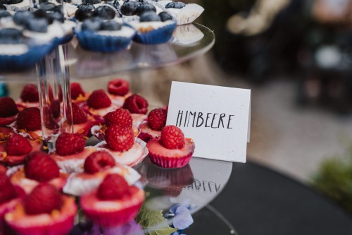 Ein Tisch mit Muffins mit Himbeeren drauf.
