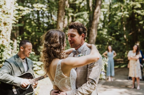 Ein Brautpaar umarmt sich und ein Mann spielt Gitarre.