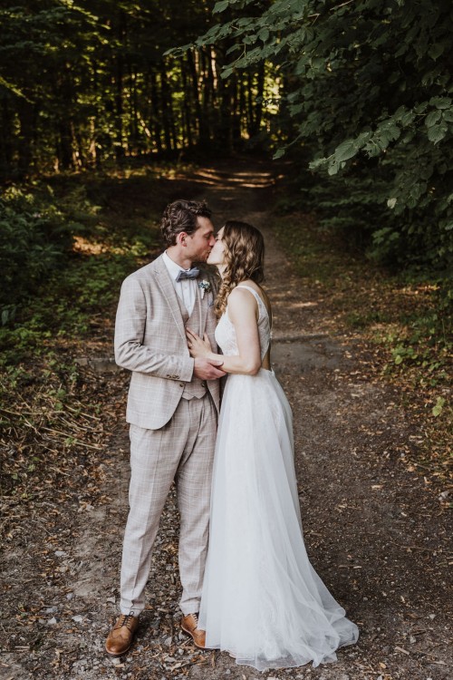 Ein Brautpaar küsst sich im Wald.