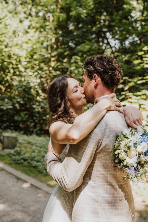 Ein Brautpaar küsst sich im Wald.