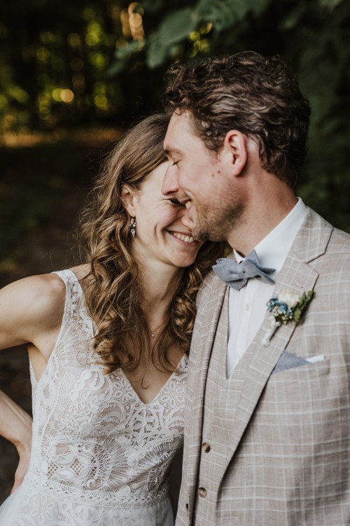 Ein Brautpaar steht nebeneinander im Wald.