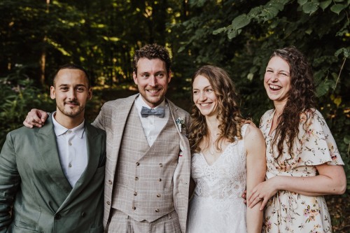 Ein Brautpaar und die Trauzeugen stehen nebeneinander im Wald.