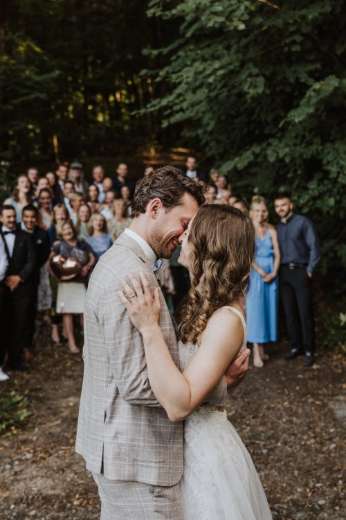 Ein Brautpaar küsst sich und eine Gruppe von Menschen schaut zu.