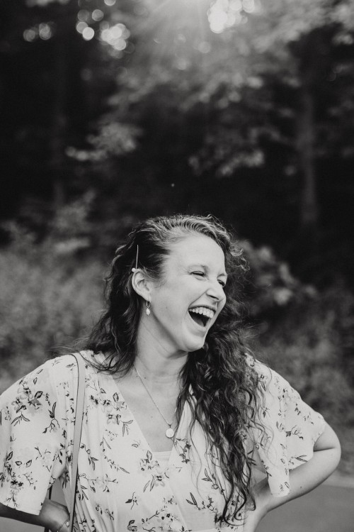 Eine Frau steht im Wald und lacht.