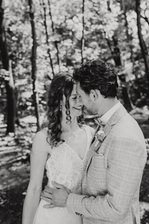 Ein schwarz-weißes Bild von einem kuschelndem Brautpaar.